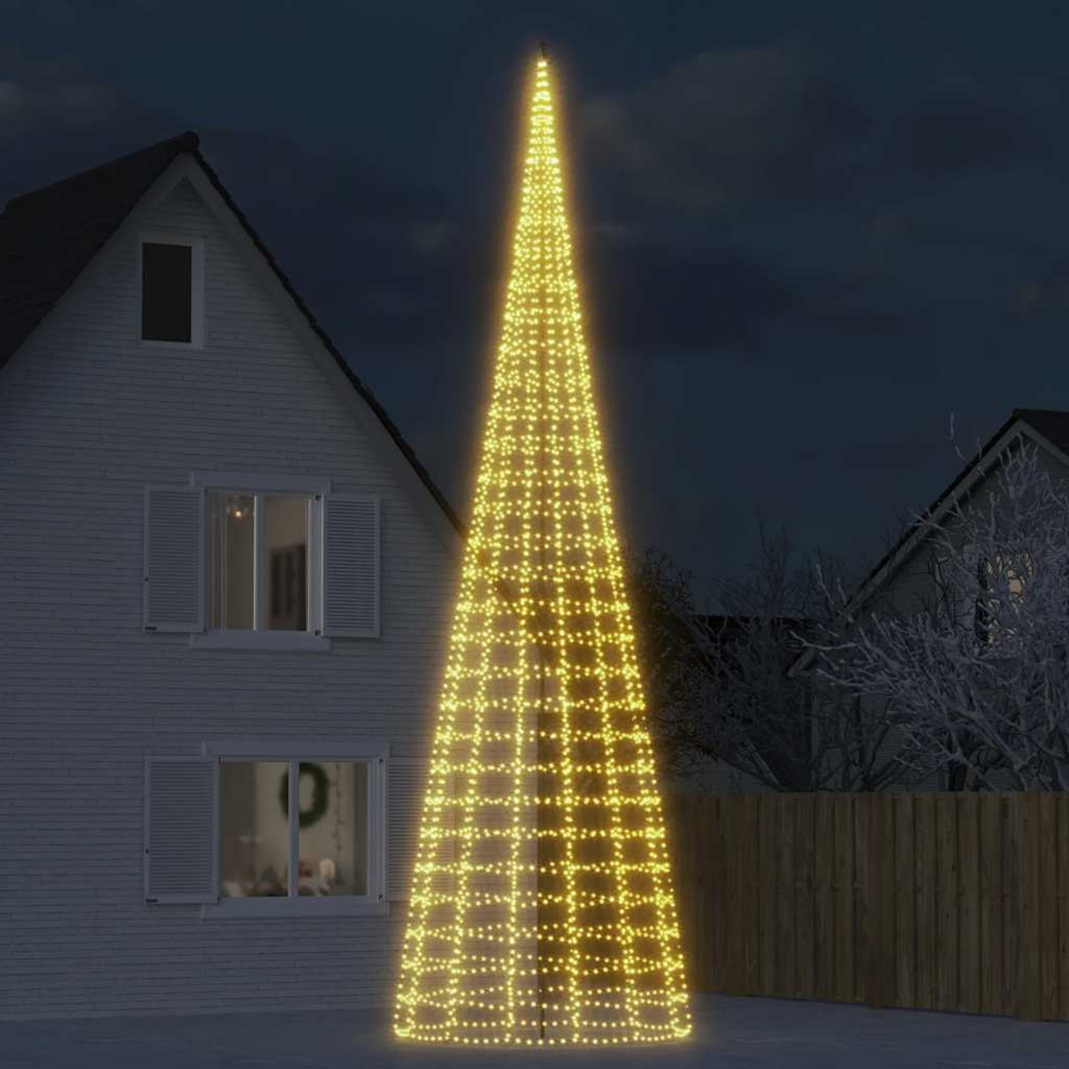 Ein beleuchteter Tannenbaum aus Lichtern steht vor einem Haus bei Nacht.