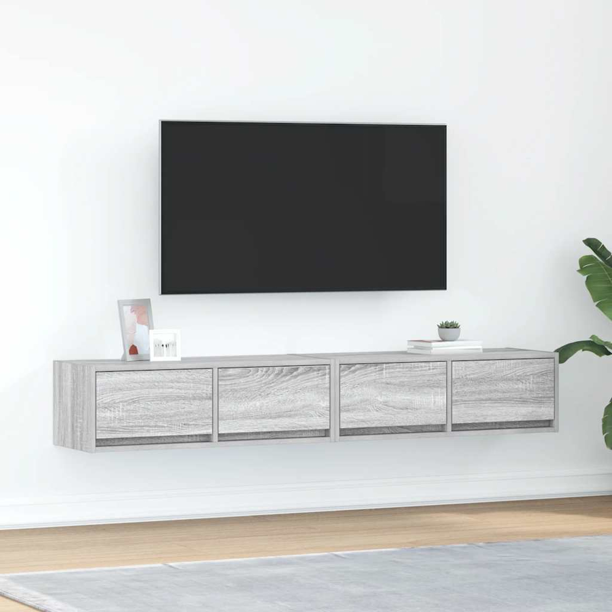 Ein schwebendes graues TV-Möbel mit vier Schubladen unter einem schwarzen Fernseher.