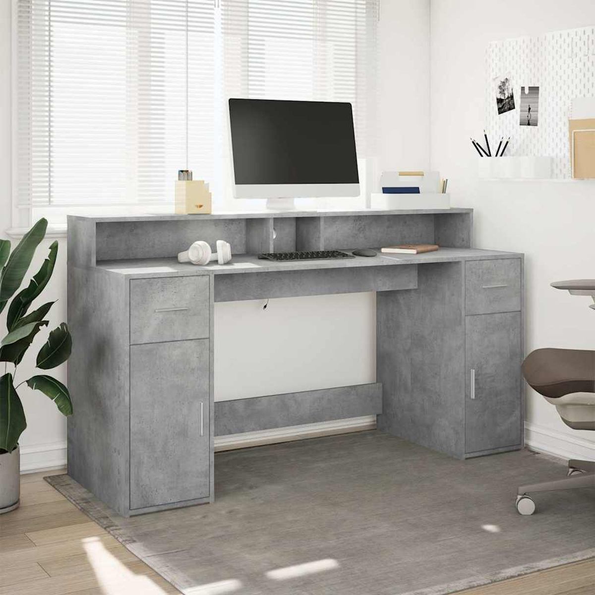 Grauer Schreibtisch mit Computer, Tastatur, Kopfhörern und Pflanzen.