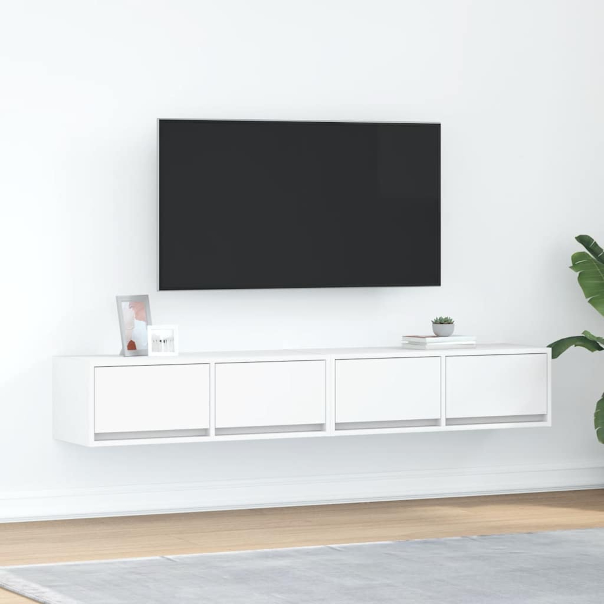 Ein moderner weier Wand-TV-Schrank mit vier Schubladen unter einem groen schwarzen Fernseher.