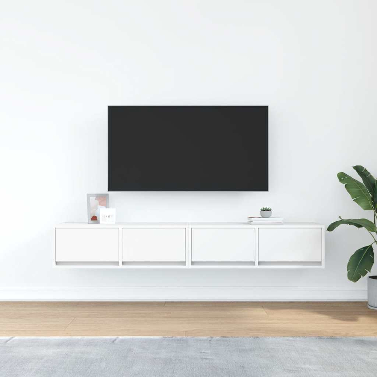 Ein moderner Wohnraum mit einem Fernseher an der Wand über einem weißen Schrank.