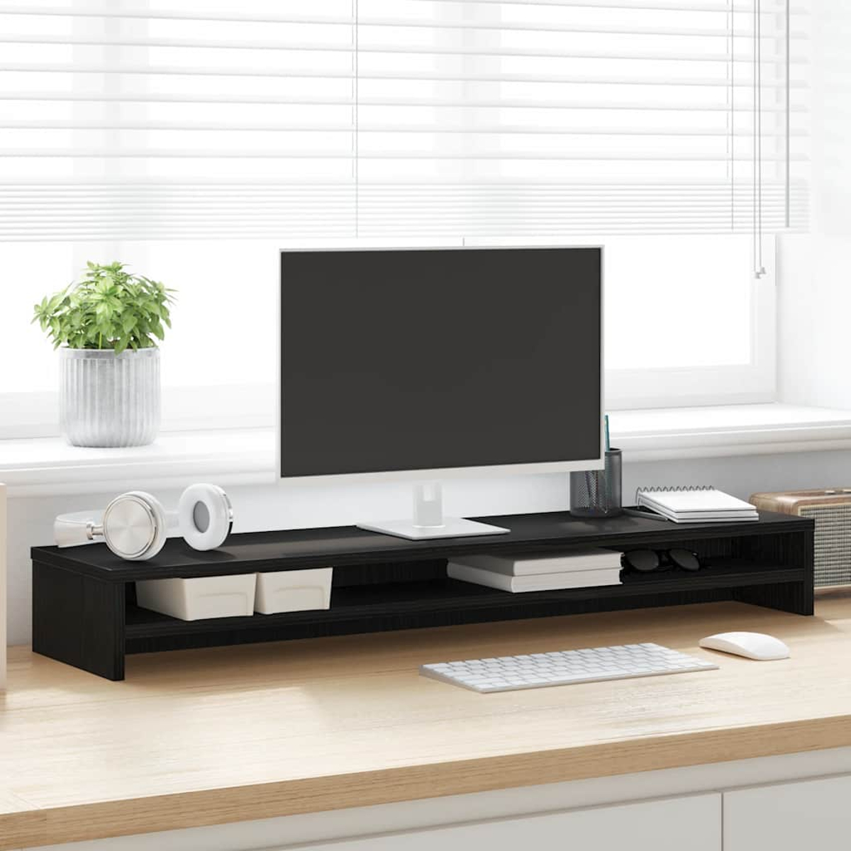Ein schwarzer Monitorständer mit einem Monitor, Kopfhörern, Pflanzen und Büromaterial.