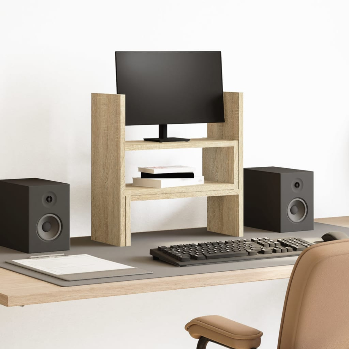 Ein Schreibtisch mit Monitor, Tastatur, Lautsprechern und Büchern.