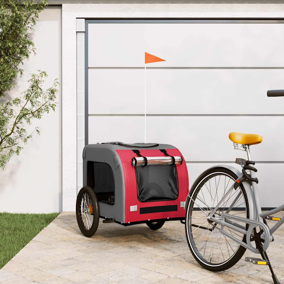 Ein roter und grauer Fahrradanhänger mit einem orangefarbenen Wimpel steht neben einem Fahrrad.