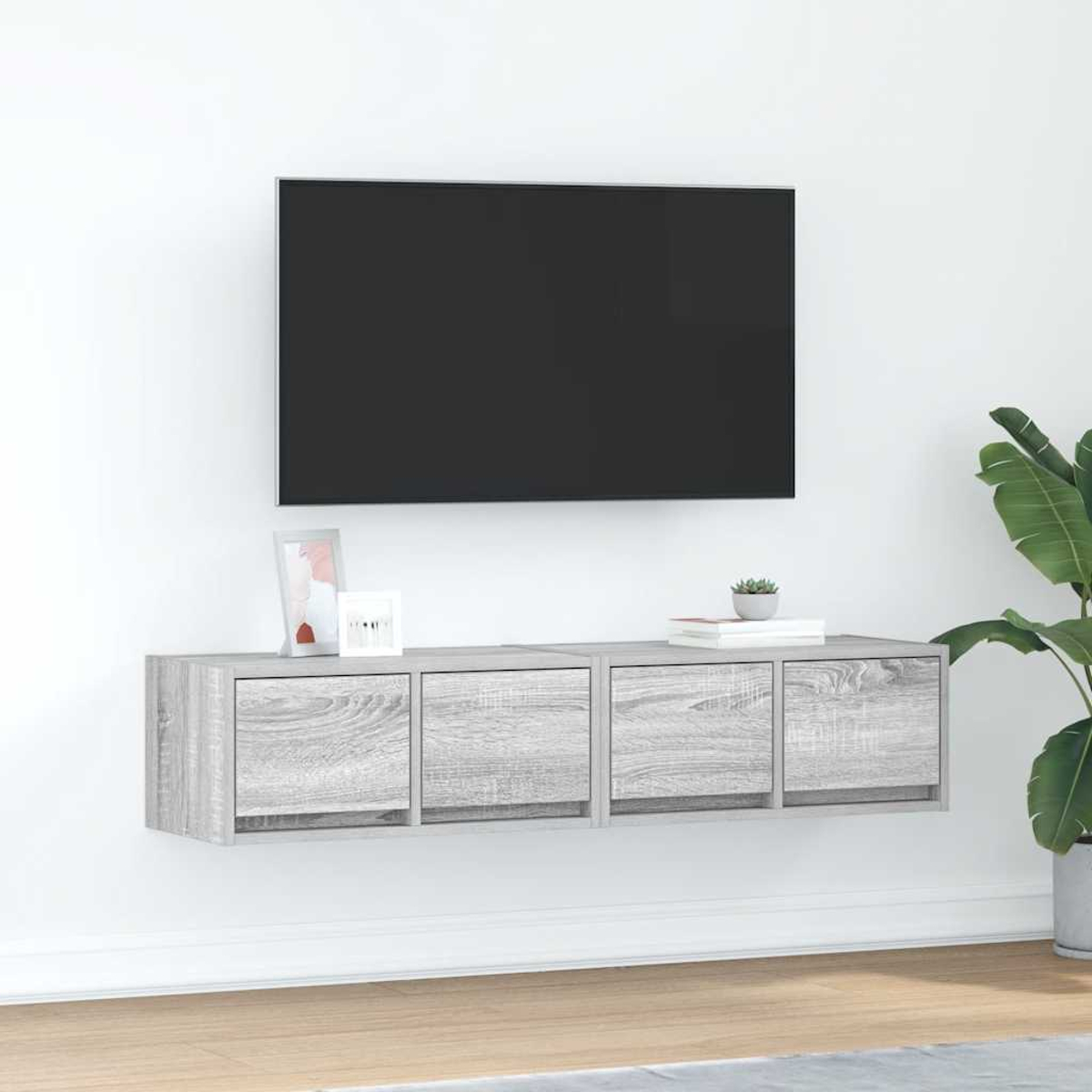 Ein hängendes graues TV-Möbel mit vier Türen unter einem schwarzen Fernseher.