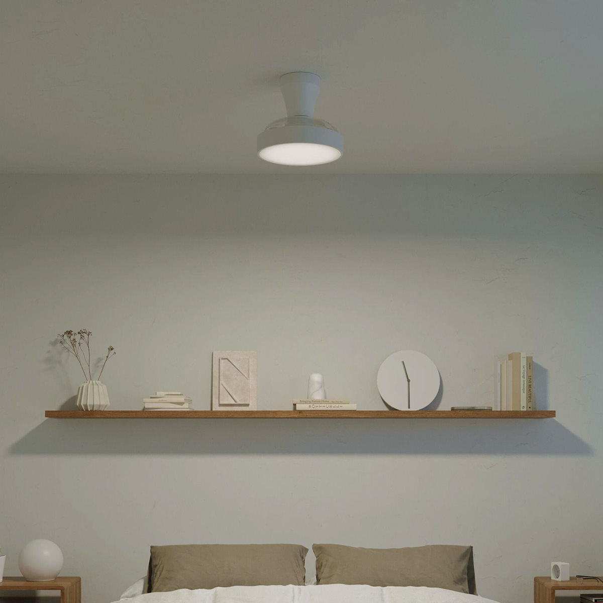 Una repisa flotante muestra decoración, libros y un reloj. Una luz de techo está arriba.