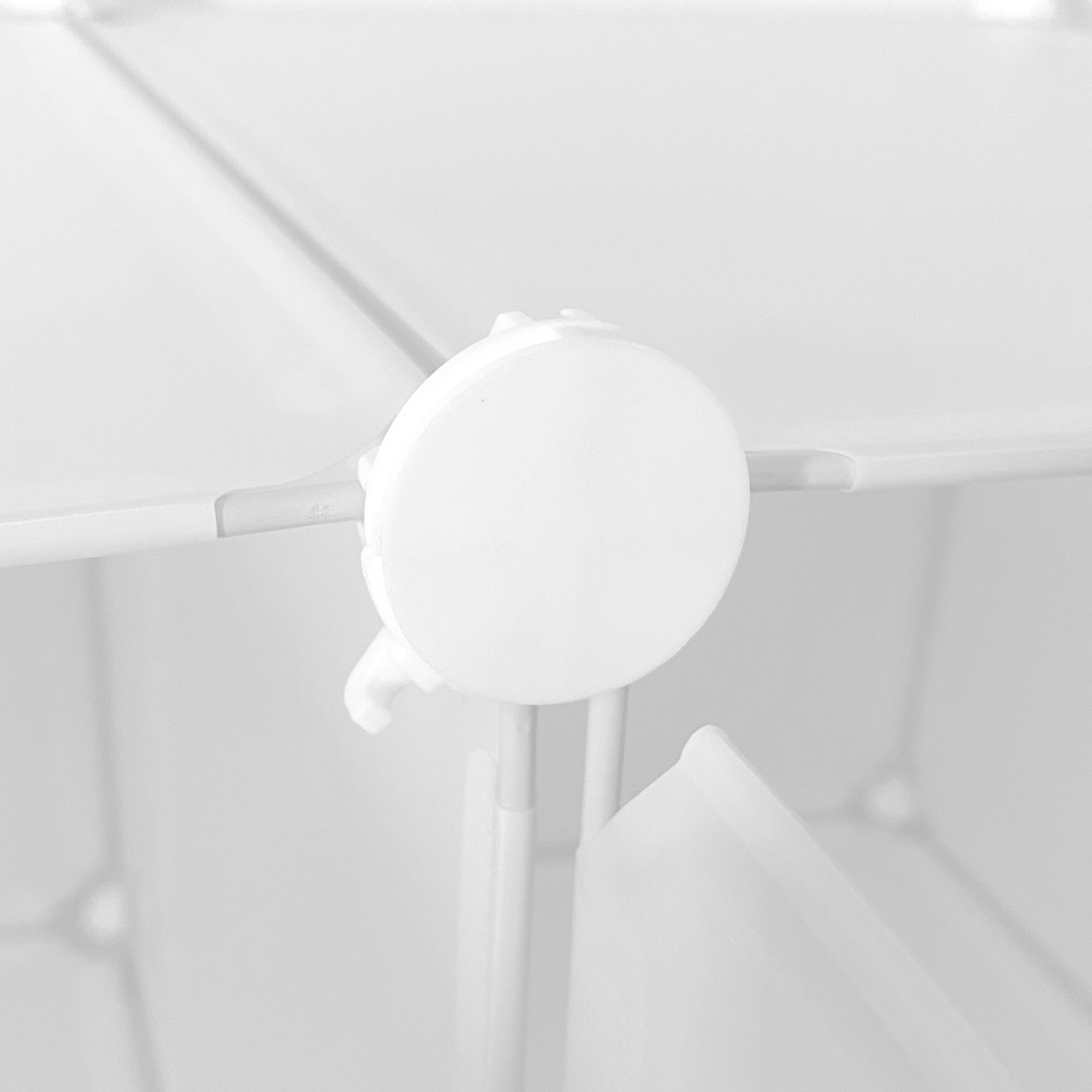 Primer plano de un conector de plástico blanco en una estantería modular.