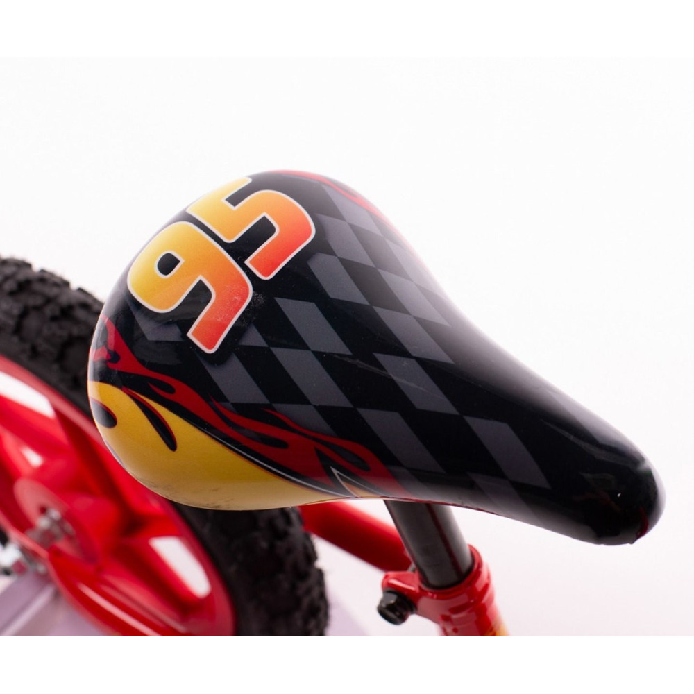 Zbliżenie na siodełko roweru dziecięcego z naklejkami płomieni i numerem 95.