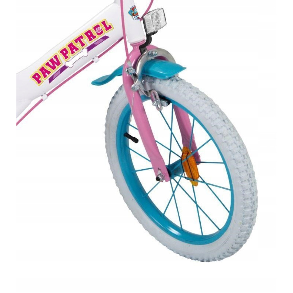 Zbliżenie białego roweru dziecięcego z różową ramą, niebieskimi obręczami i logo Psiego Patrolu.