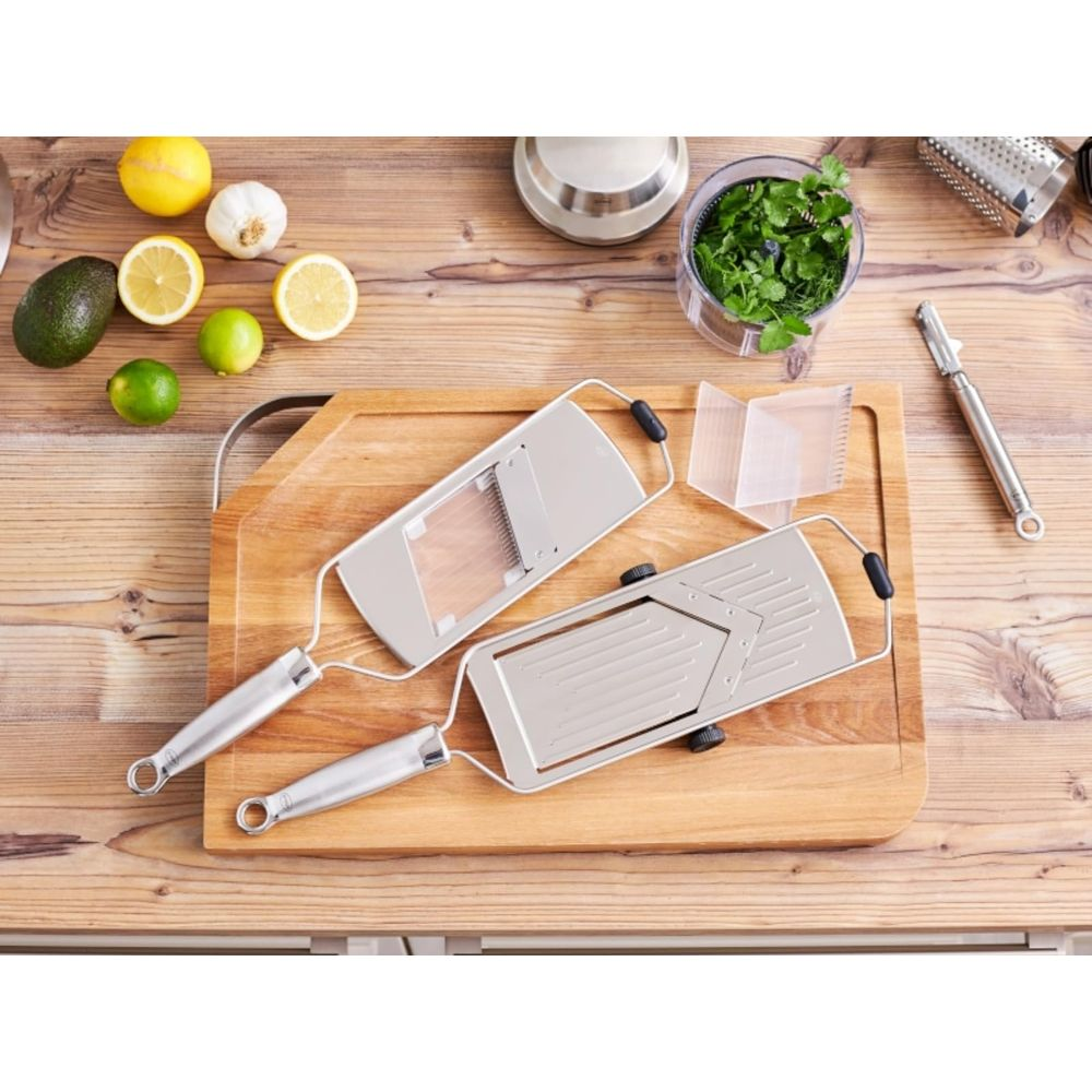 Utensili da cucina, comprese due mandoline su tagliere di legno con limoni, aglio, lime ed erbe aromatiche.