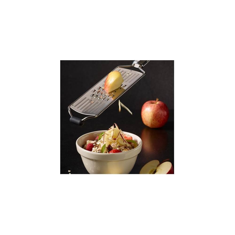 Mela grattugiata sopra una ciotola di muesli e frutti di bosco.