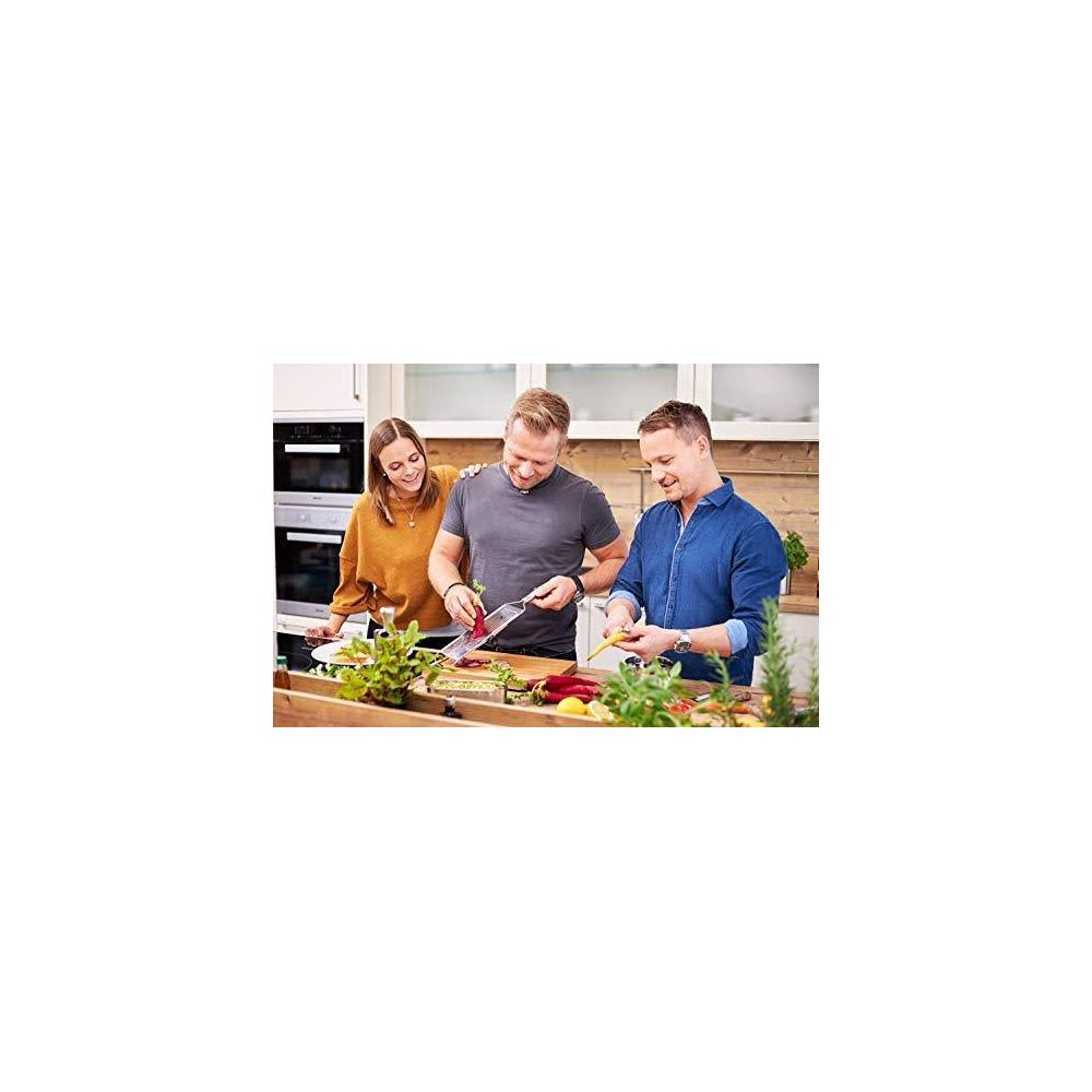 Tre persone in cucina preparano cibo, tagliando verdure.