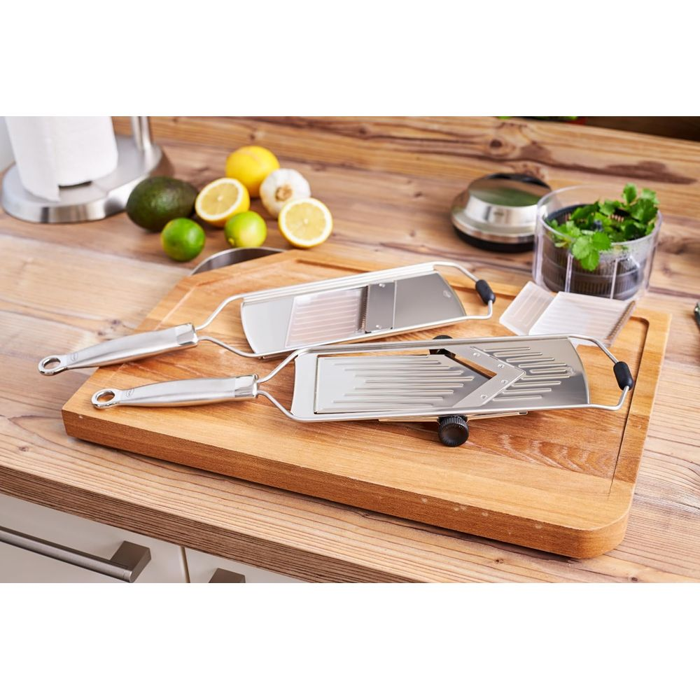 Due mandoline in metallo con manici in legno su tagliere con agrumi e avocado.