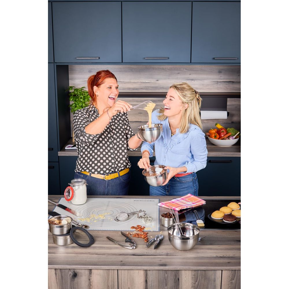 Due donne preparano pastella in cucina. Una versa la pastella, l'altra tiene una ciotola.