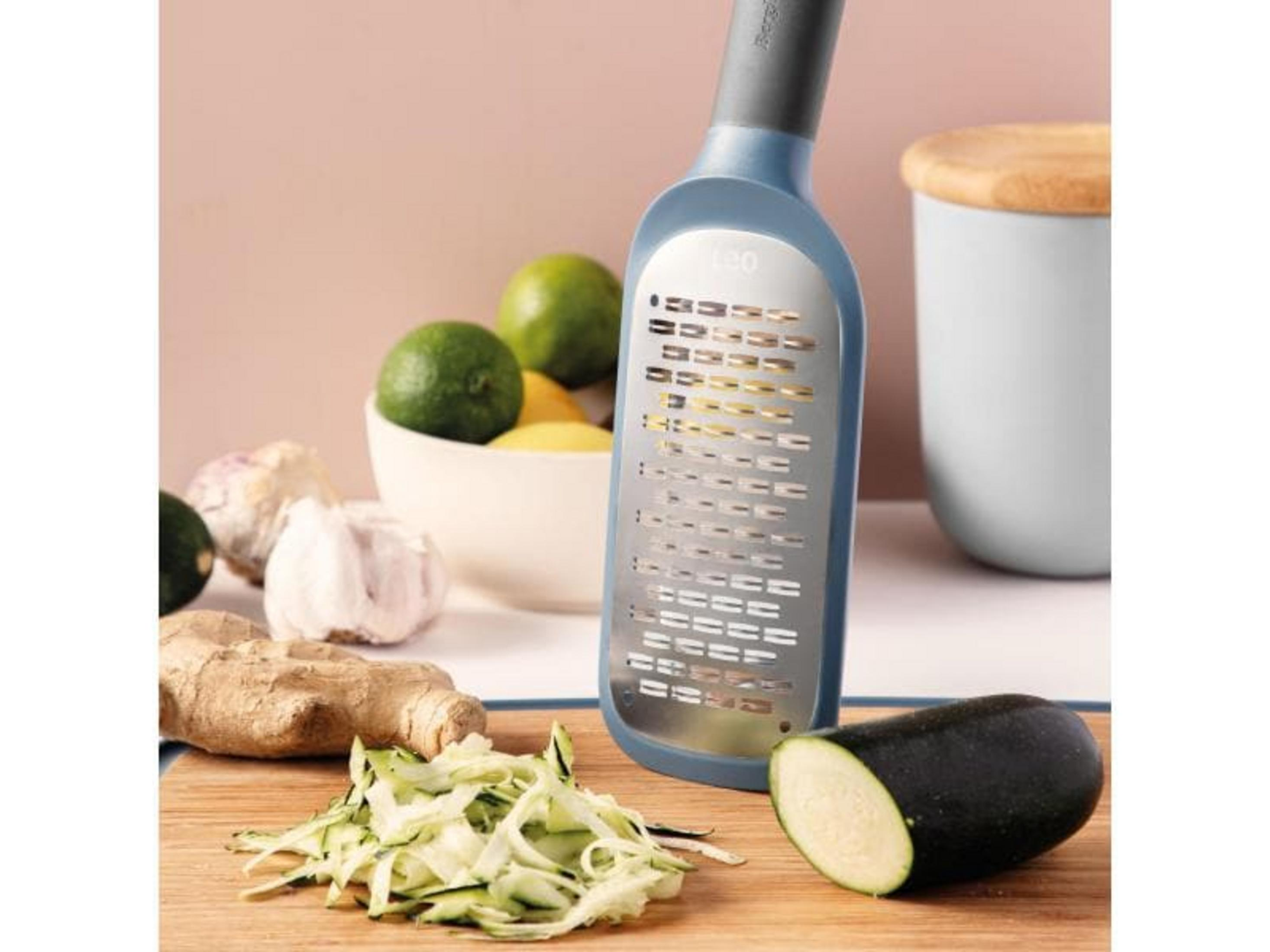 Una grattugia blu con zucchine, zenzero e aglio.