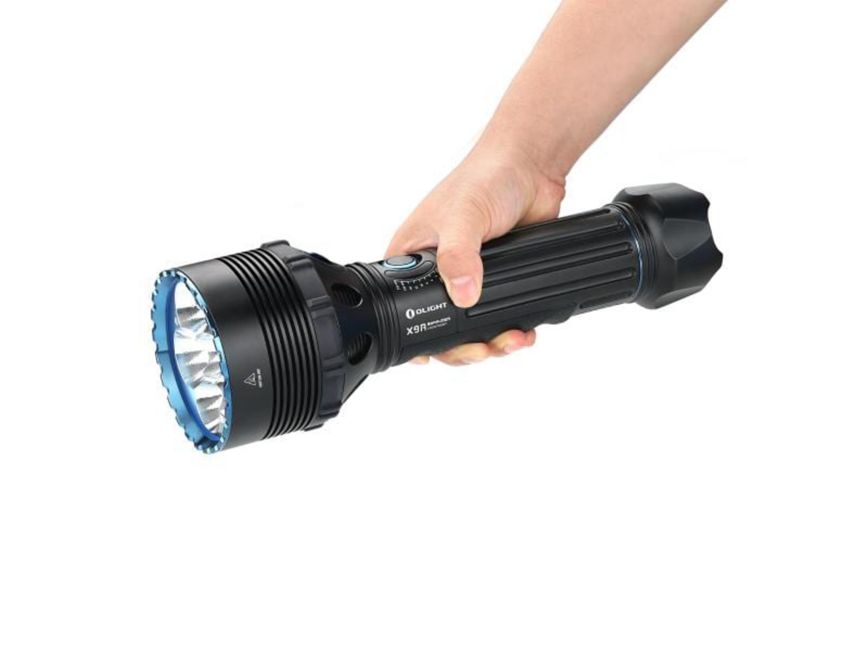 Une main tient une grande lampe de poche noire avec des accents bleus.