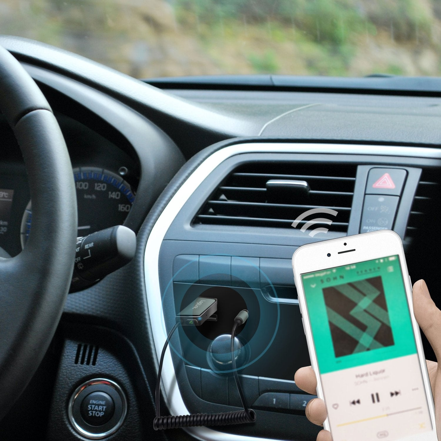 Hand houdt smartphone met muziekapp in auto. Laadadapter is aangesloten.