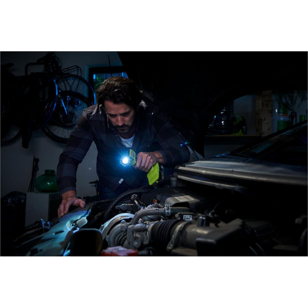 Homme lampe torche inspectant moteur voiture garage.