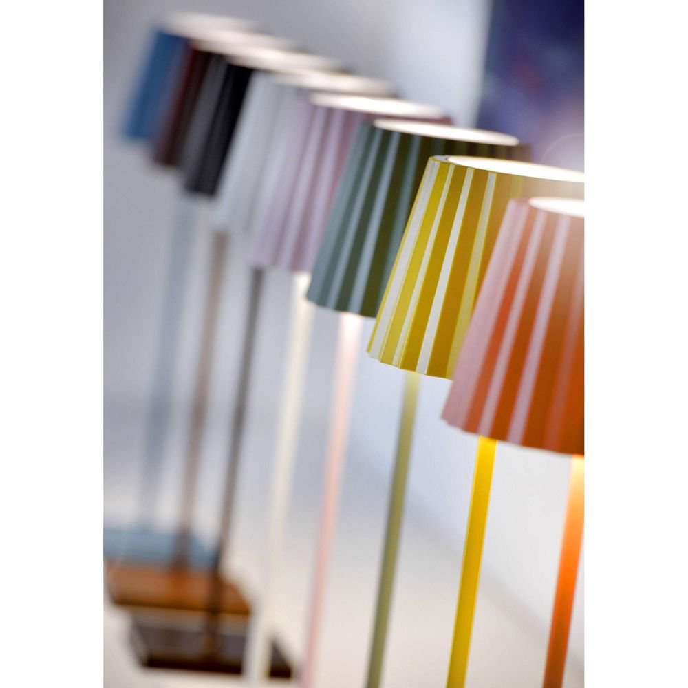 Diverse lampade da terra in vari colori, dal blu all'arancione, sono allineate.