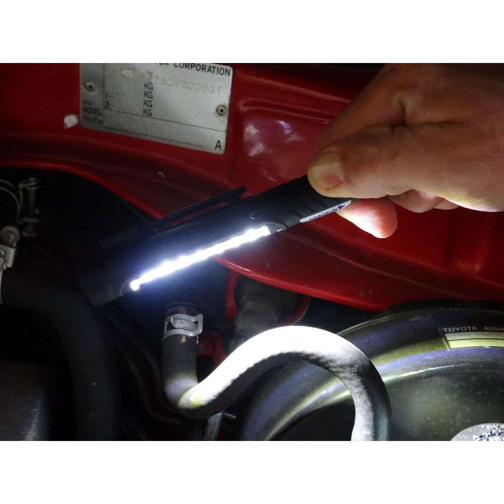 Una mano tiene una torcia con luce intensa in un vano motore rosso.