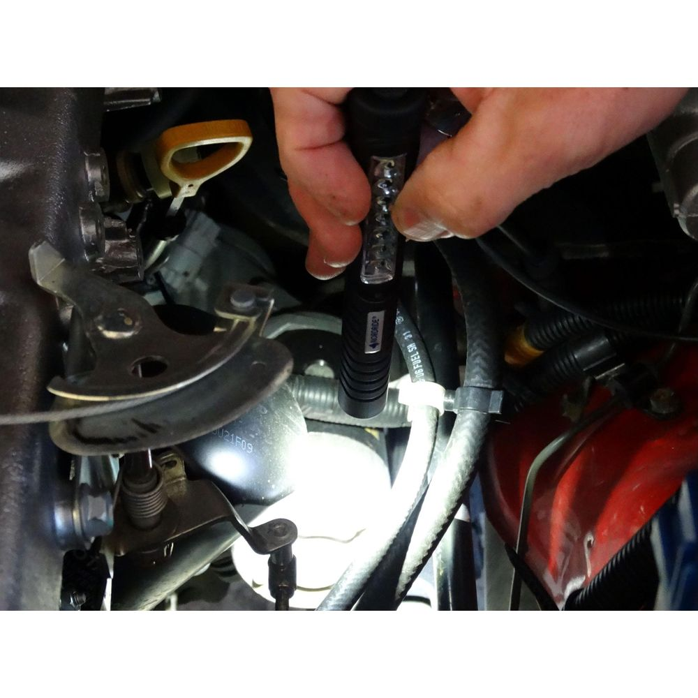 Una mano tiene una torcia nel vano motore, illuminando un filtro dell'olio.
