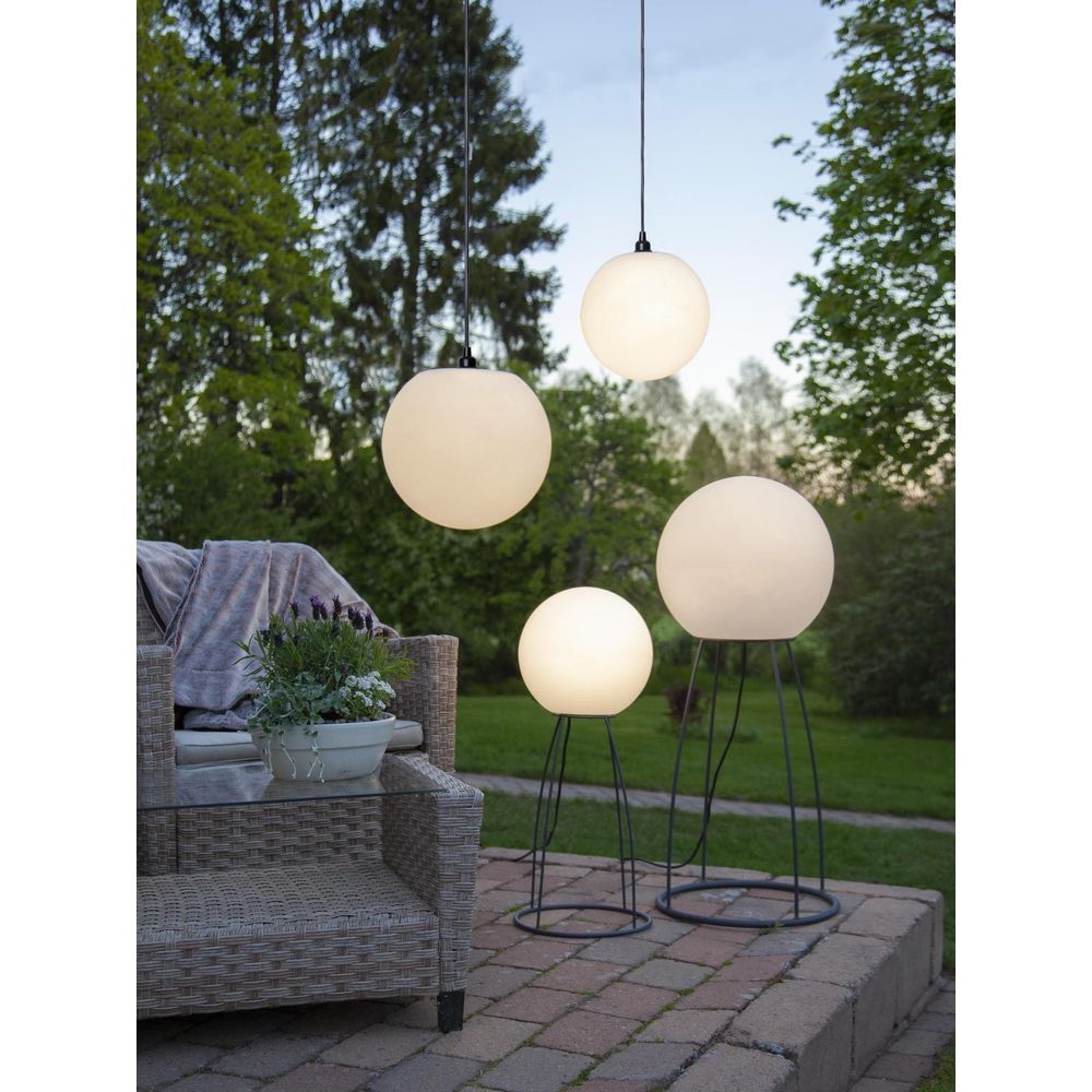 Terrasse mit Lounge-Sessel, Tisch und kugelförmigen Lampen in verschiedenen Größen.