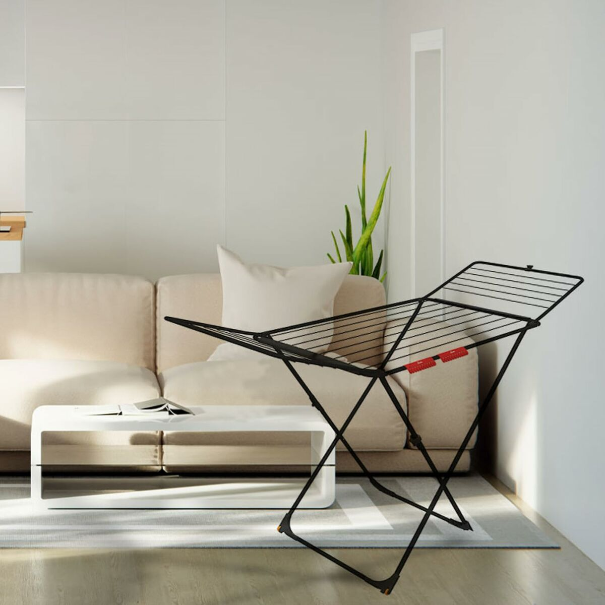 Czarny stojak na pranie przed beżową sofą, obok biały stolik.