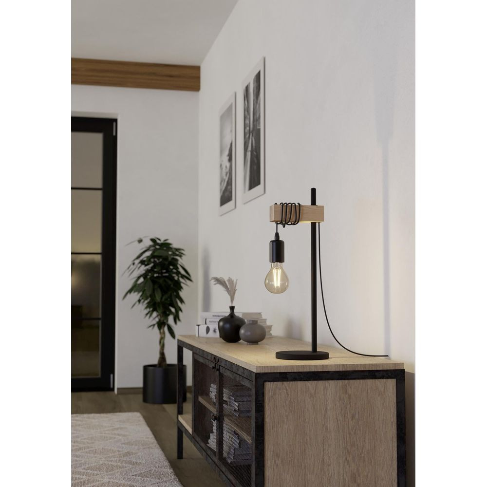 Eine Stehlampe mit Holzakzent und sichtbarer Glühbirne steht auf einem Sideboard.