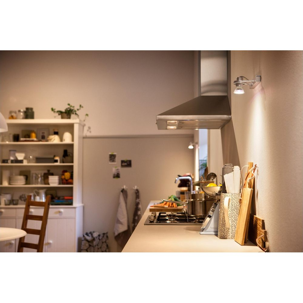 A bright kitchen featuring a gas stove, exhaust hood, and shelves stocked with dishes.
