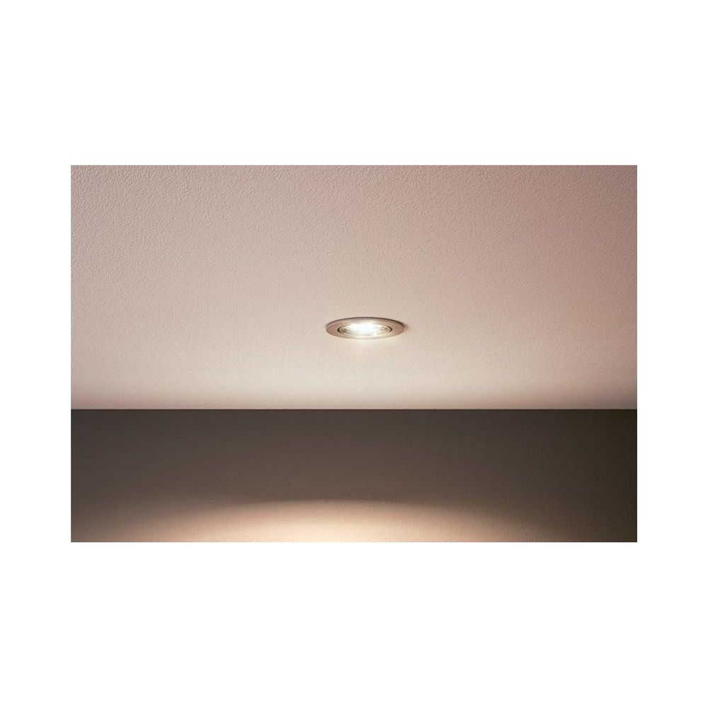 A recessed light illuminates a ceiling above a dark wall.