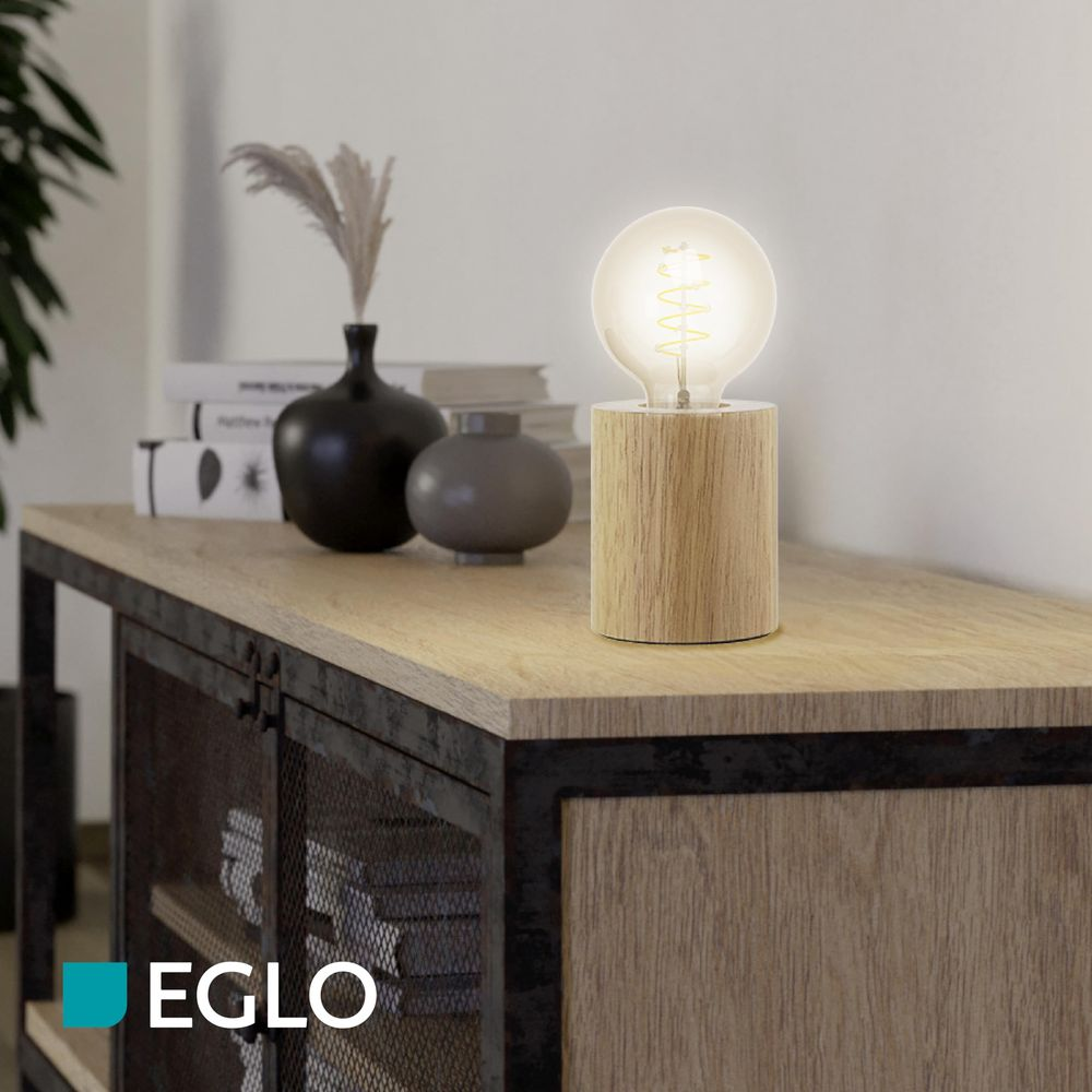 Eine Lampe mit Holzbock steht auf einem Tisch neben Vasen.