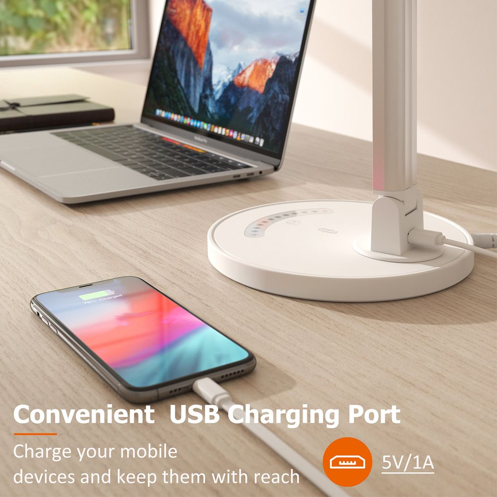 Ein Smartphone und Laptop auf einem Schreibtisch, mit einem weißen Lampensockel mit USB-Anschluss.