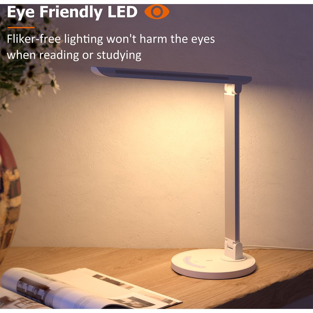 Eine weiße LED-Schreibtischlampe auf einem Holztisch mit einem Buch.