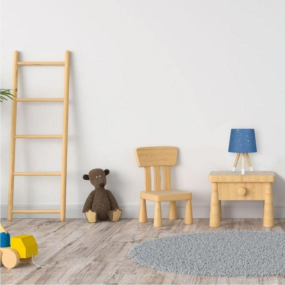 Eine Holzleiter, Teddybär, Stuhl und Spielzeugwagen in einem Raum mit blauer Lampe.