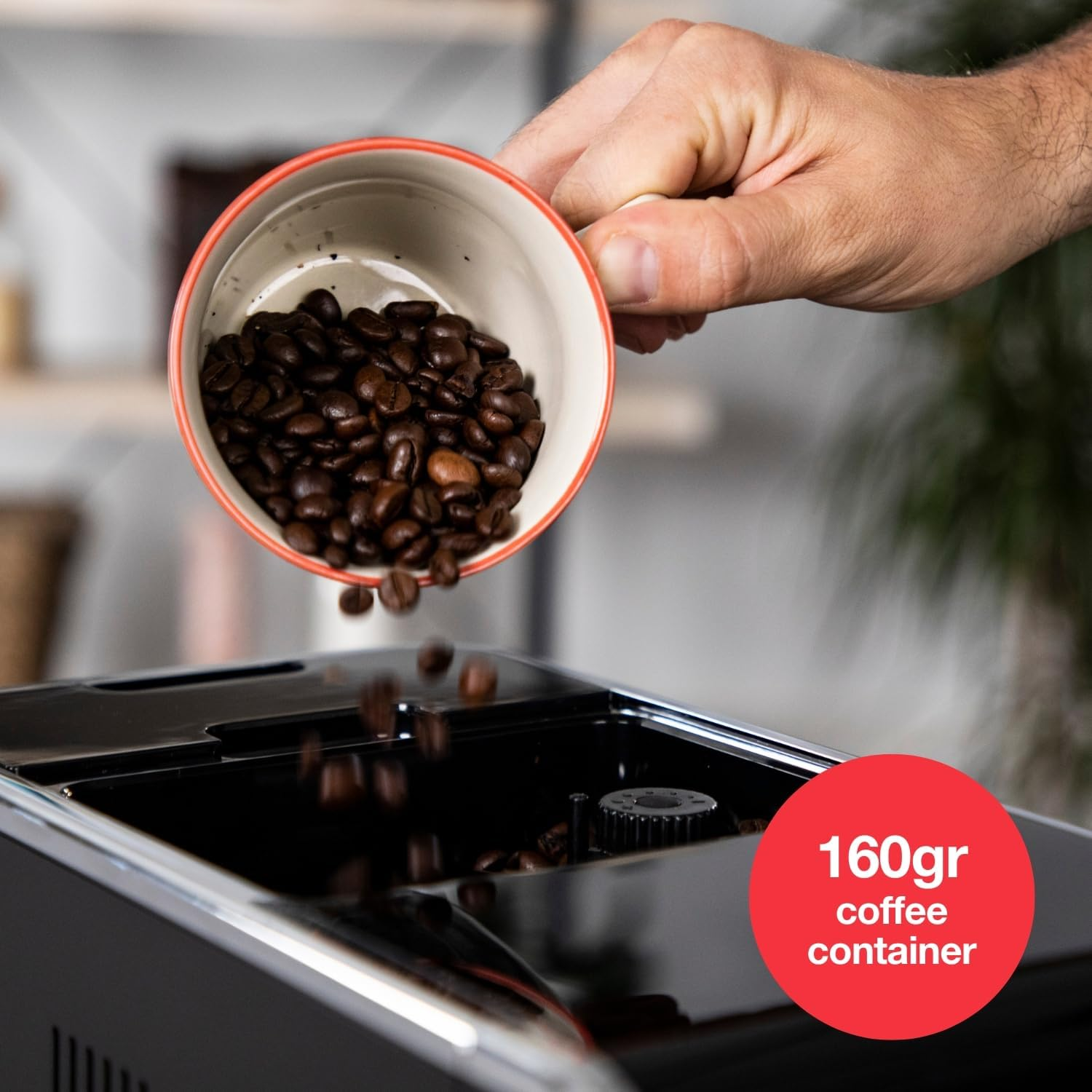 Una mano vierte granos de café de una taza a una cafetera.