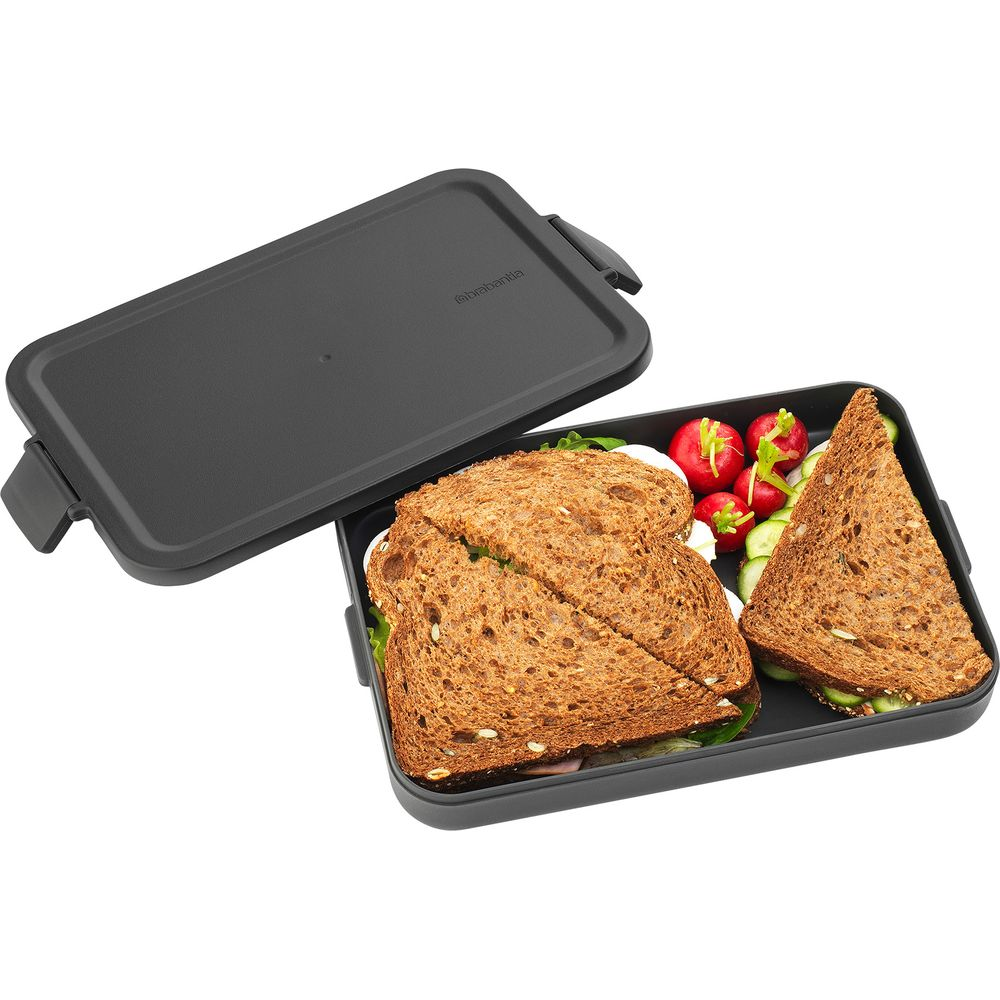 Un contenitore per il pranzo nero con coperchio, riempito con panini e ravanelli.