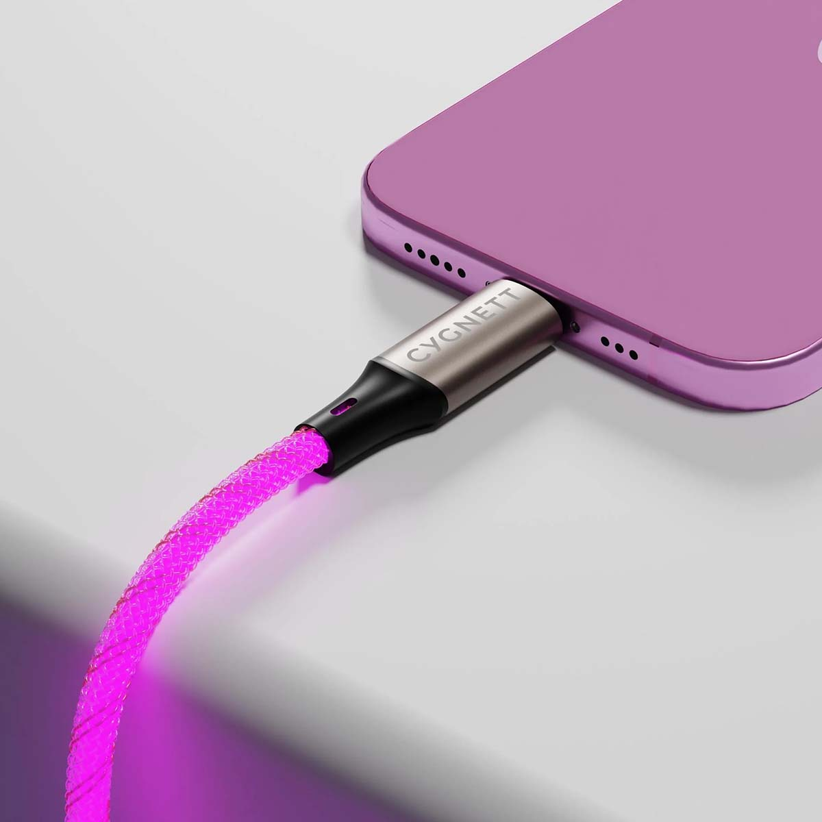Un telefono viola si carica con un cavo rosa luminoso. Il cavo ha il testo "CYGNETT".