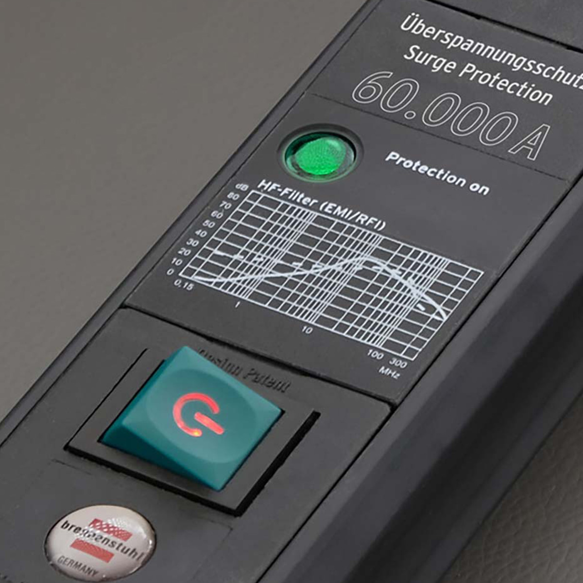 Dispositivo nero con LED verde, pulsante di accensione con simbolo "G" rosso e grafico di frequenza.