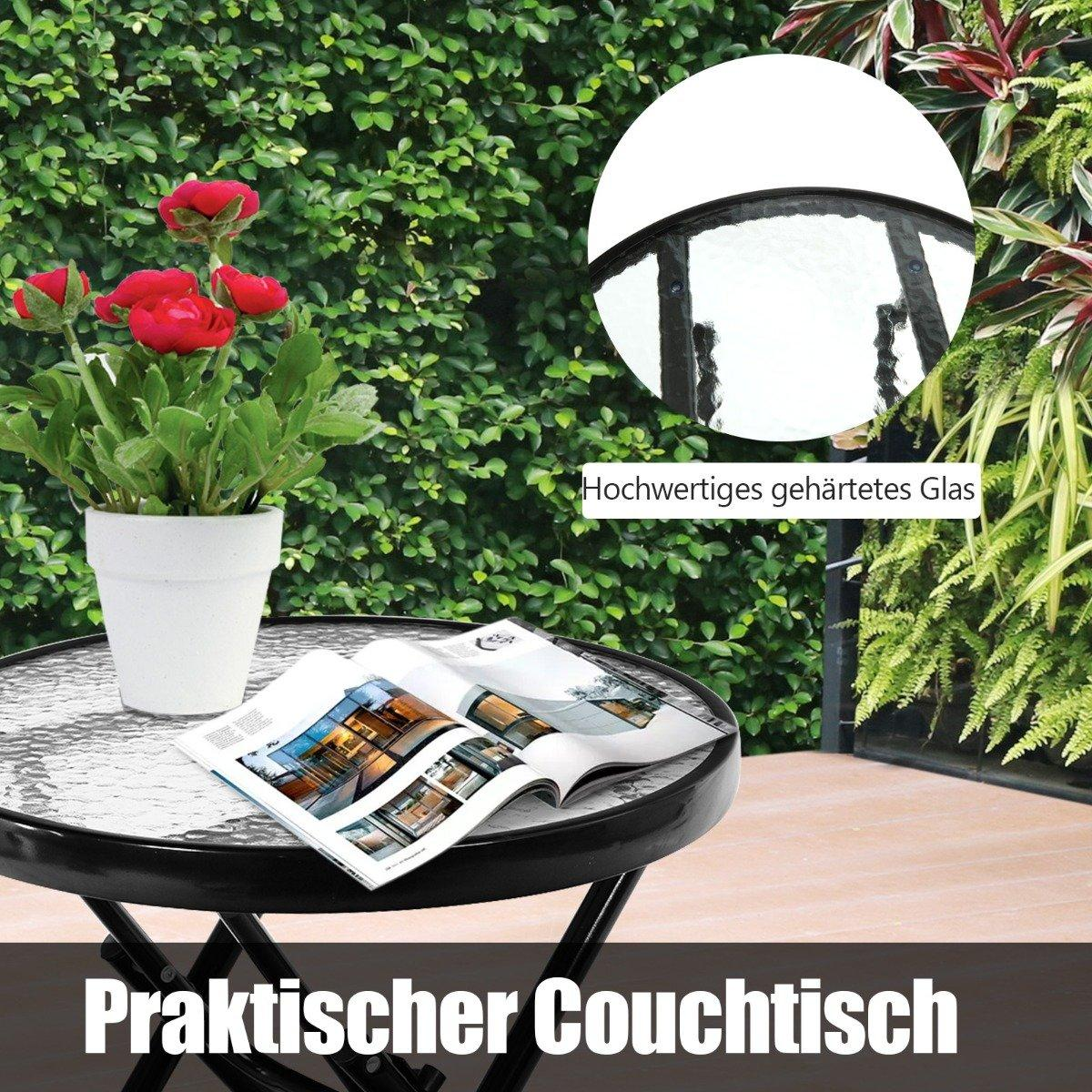 A round glass-top table with a magazine and a potted plant on it, outdoors.