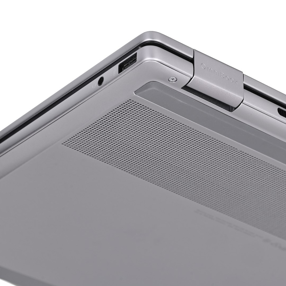 Zbliżenie srebrnego rogu laptopa, pokazujące port USB i kratkę głośnika.