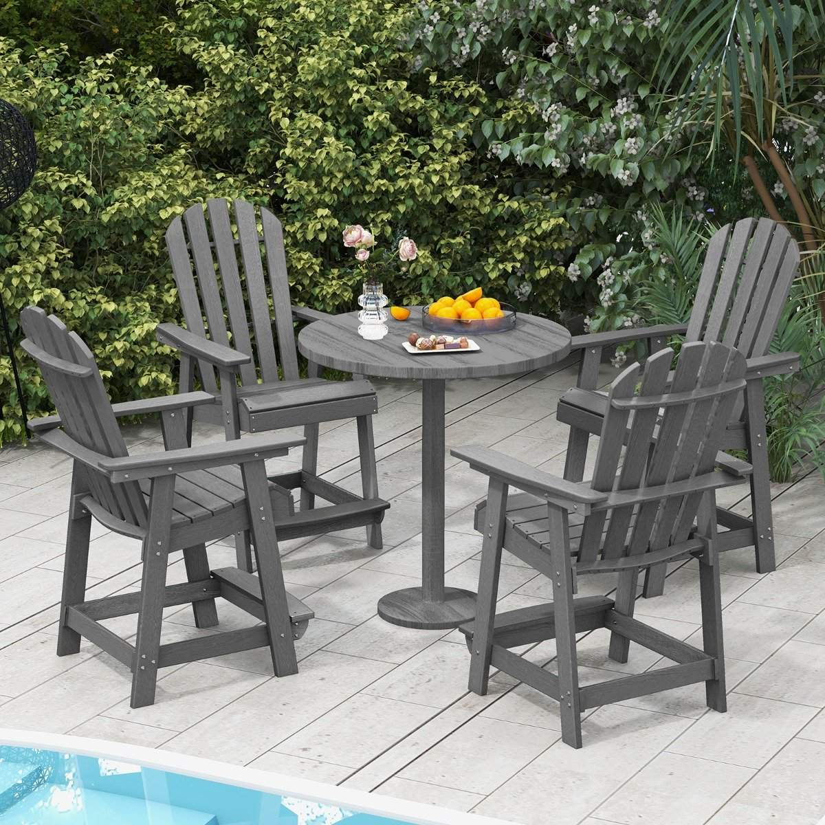 Four gray Adirondack chairs surround a round table with fruit and drinks on a patio.