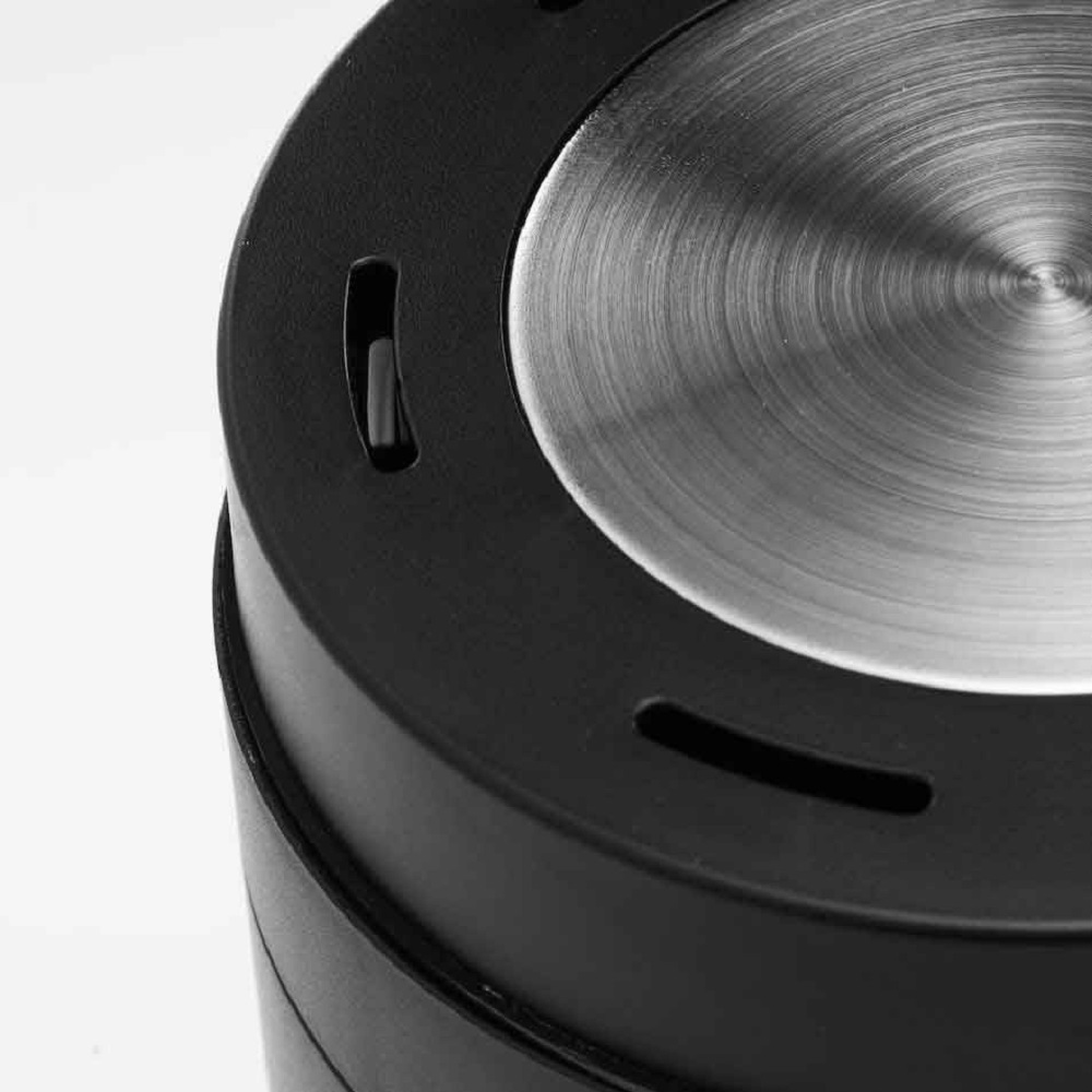Close-up van een zwart apparaat met een geborsteld metalen oppervlak bovenop.