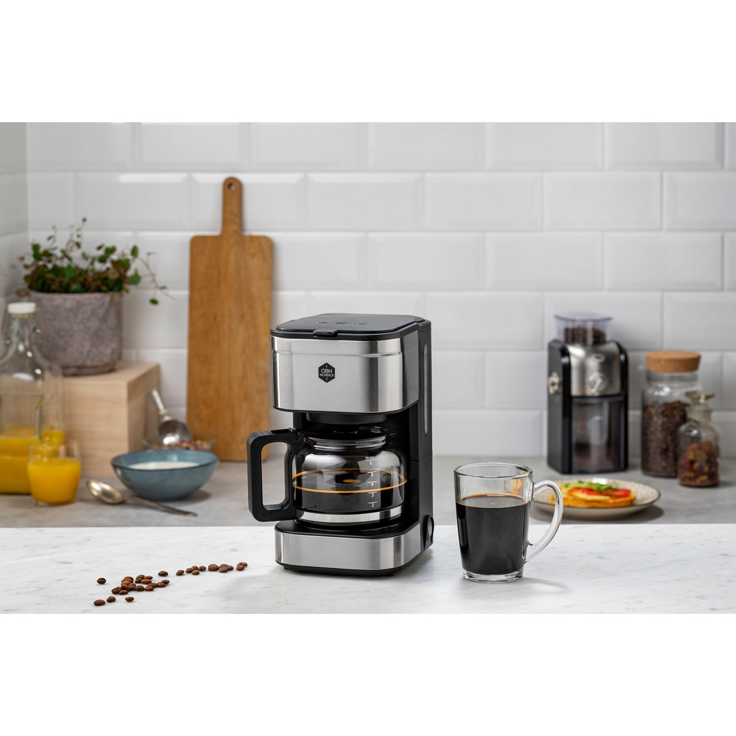 Koffiezetapparaat met glazen kan, kop koffie, koffiebonen en sap.