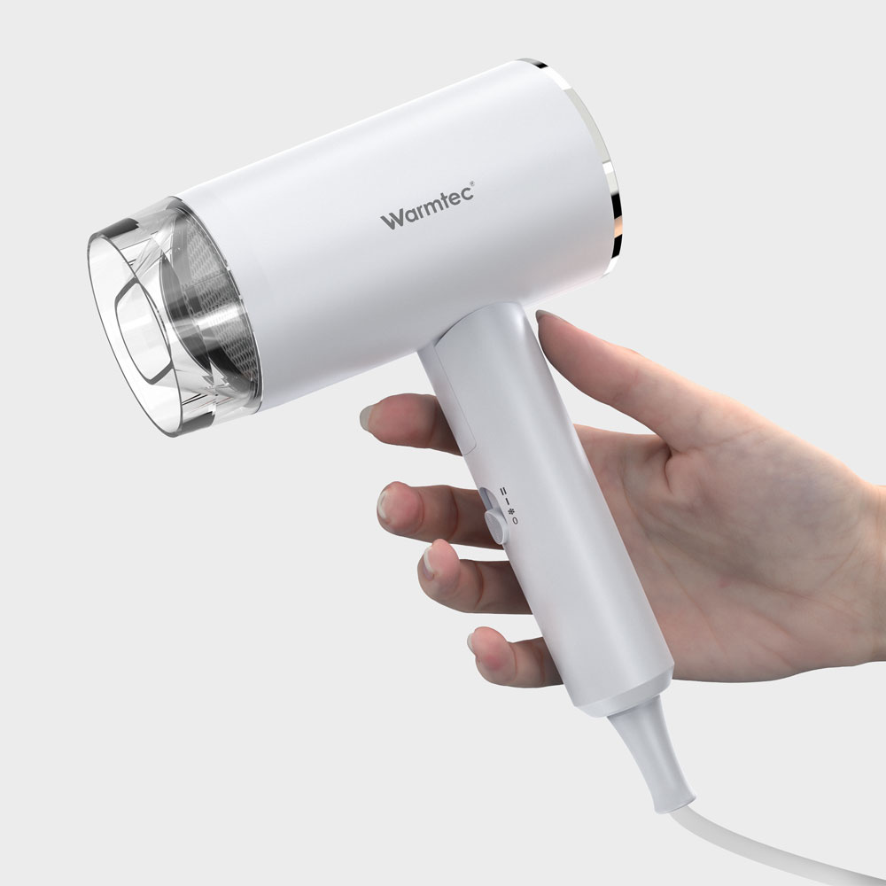 Dłoń trzyma białą suszarkę do włosów z przezroczystą dyszą i srebrnymi akcentami.