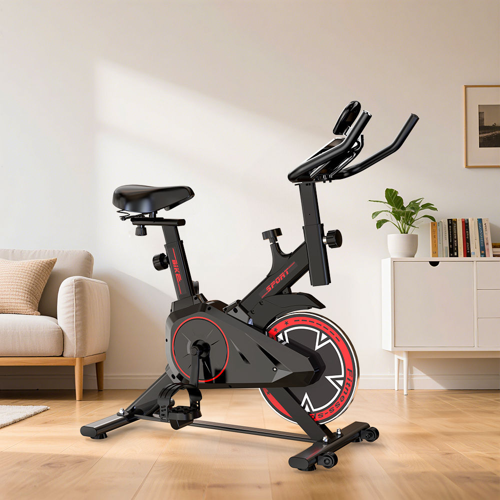 Ein schwarzes Indoor-Fahrrad mit roten Akzenten steht in einem Wohnzimmer.