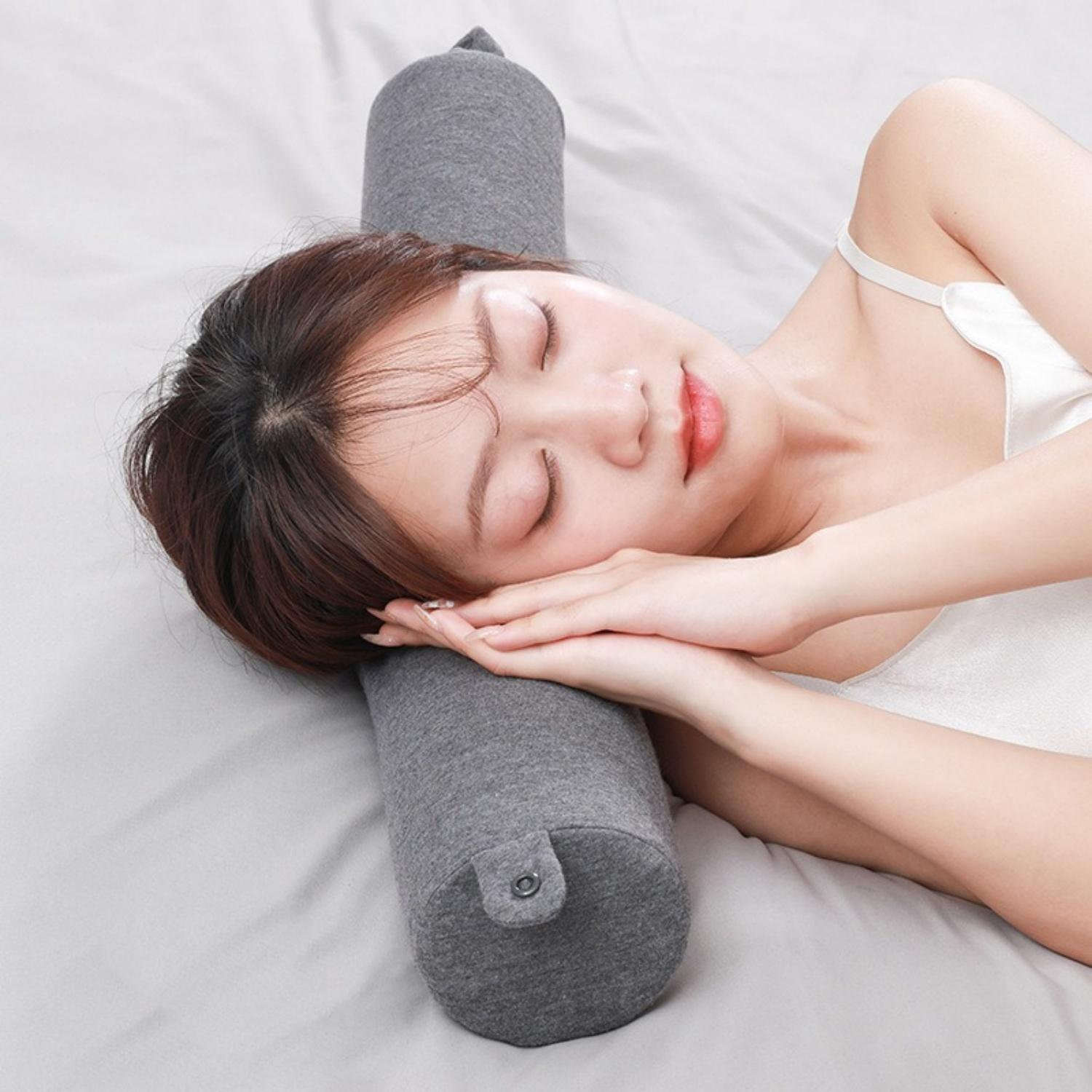 Eine Frau schläft auf einem grauen Nackenkissen auf einem Bett.