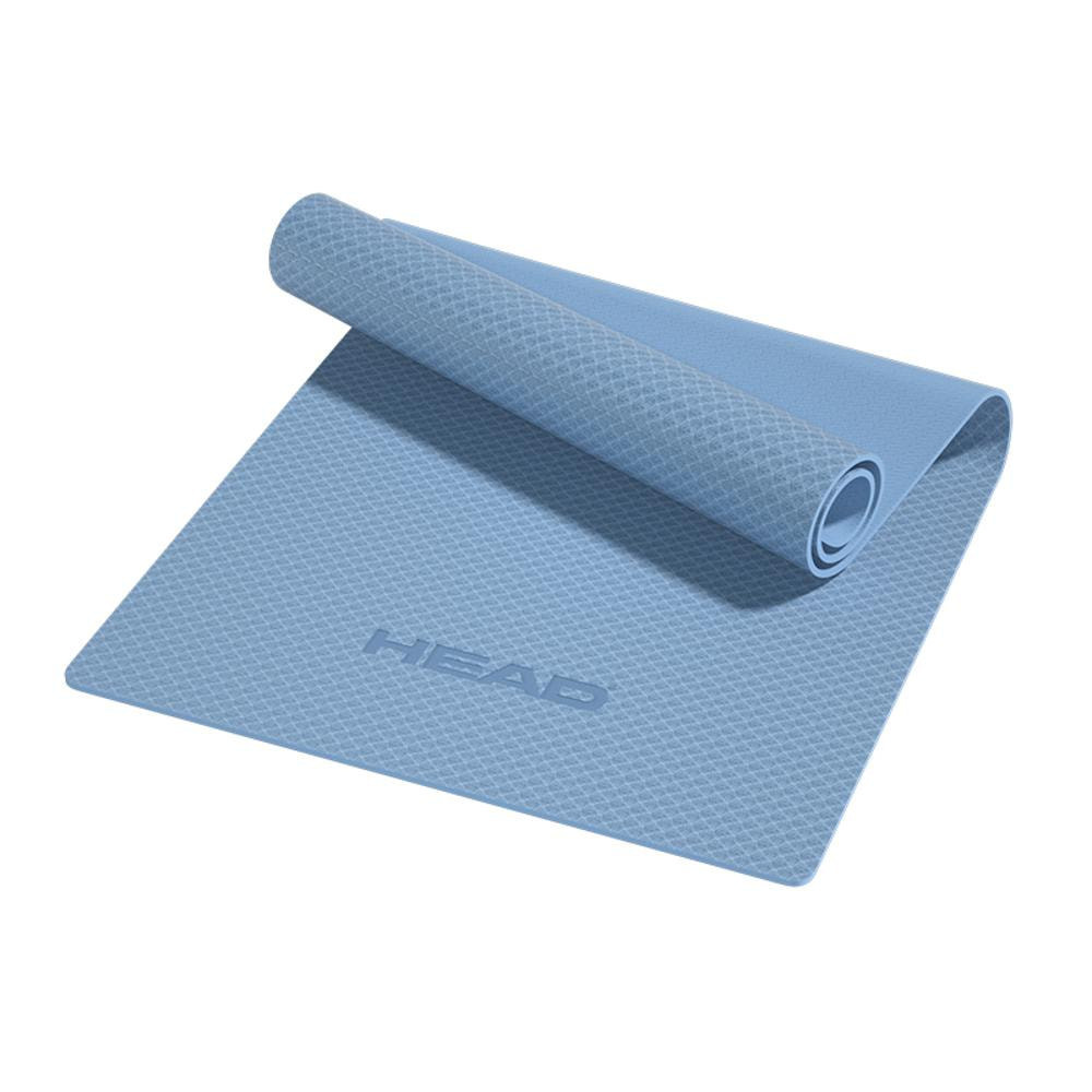 Una esterilla de yoga azul claro con la palabra "HEAD" está en el suelo.