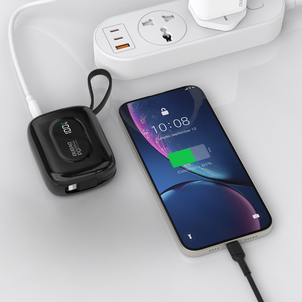 Ein schwarzes Ladegerät lädt ein Smartphone, das an eine weiße Steckdosenleiste angeschlossen ist.