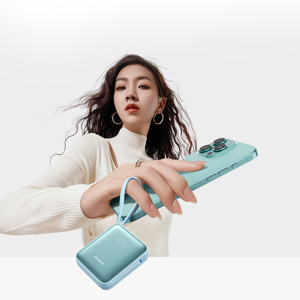 Una donna tiene uno smartphone verde acqua e un power bank verde acqua. Il power bank è attaccato da un cinturino verde acqua.