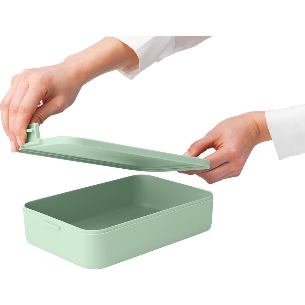 Mani aprono un contenitore verde chiaro e sollevano il coperchio.